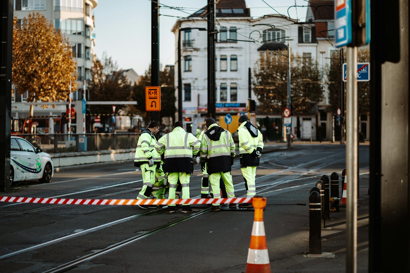 Vägarbetare står på en stadsgata nära trafikbarriärer.